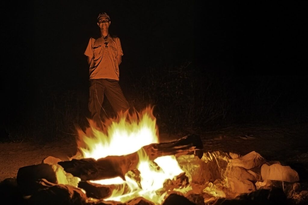 benny rebel in der wildnis afrikas am lagerfeuer auf einer fotosafari