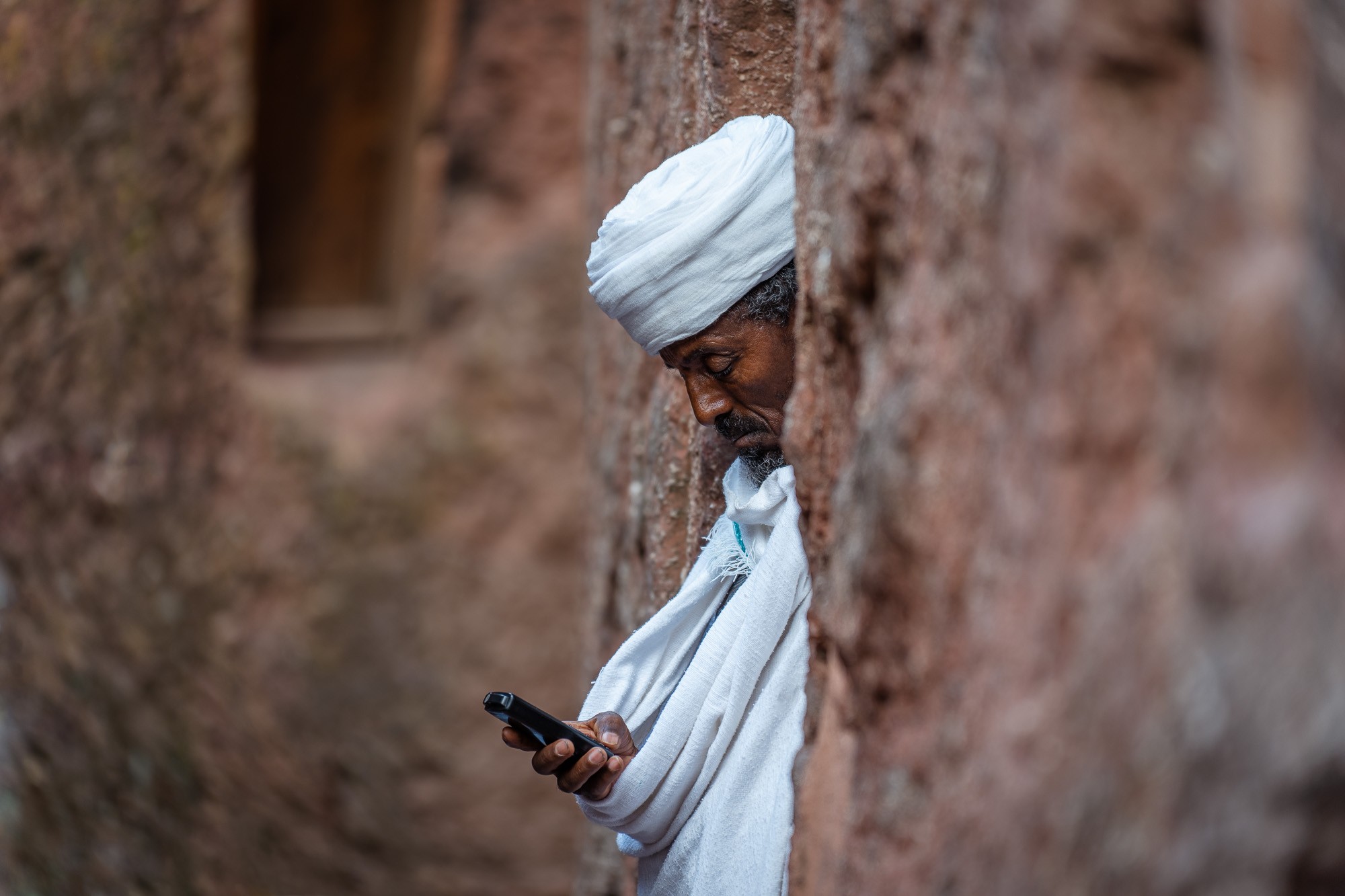 Ein Priester steht im Halbdunkel einer 850 Jahre alten Felsenkirche von Lalibela. Fotoreise durch das facettenreiche Äthiopien.