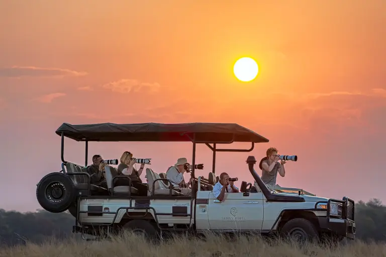 Safariauto mit Fotografen beim Sonnenuntergang auf einer Fotoreise durch Afrika fotografiert von Benny Rebel.