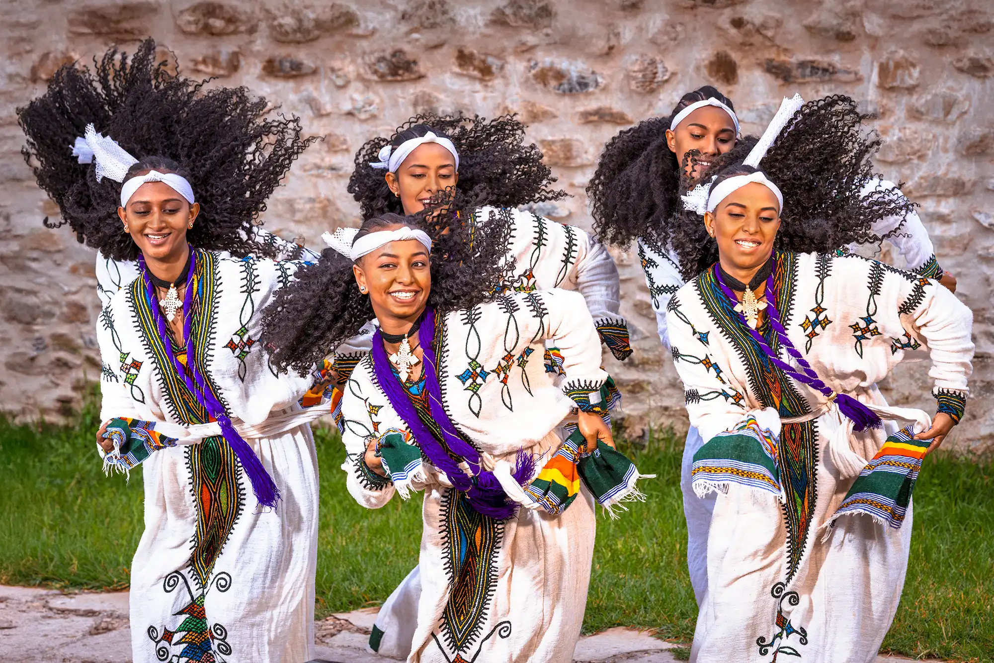 Fröhliche Tänzerinnen aus Äthiopien in traditioneller Kleidung, aufgenommen während einer Fotoreise. Ihre dynamischen Bewegungen und ihr Lächeln symbolisieren Lebensfreude, Gemeinschaft und einen hoffnungsvollen Blick ins neue Jahr.