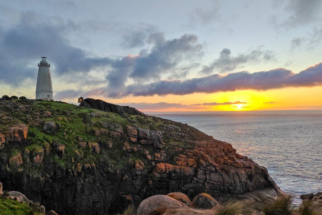 Sonnenaufgang am Leuchtturm von Kangaroo Island mit Kängurus und der wilden Küstenlandschaft Australiens im goldenen Morgenlicht.