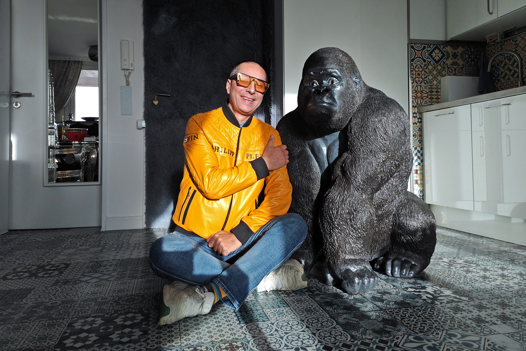 Naturfotograf Benny Rebel sitzt lächelnd neben seinem neuen lebensgroßen Gorilla Giovanni in Hannover, kurz vor seiner Fotosafari nach Südafrika und Botswana.